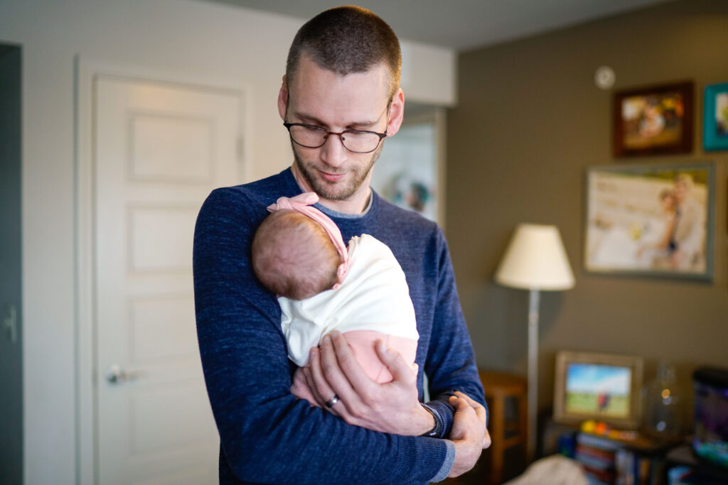 A Norman father looks lovingly at his newborn in his home.
